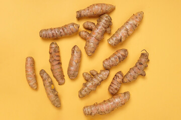 Fresh turmeric roots isolated on yellow background. High resolution photo.