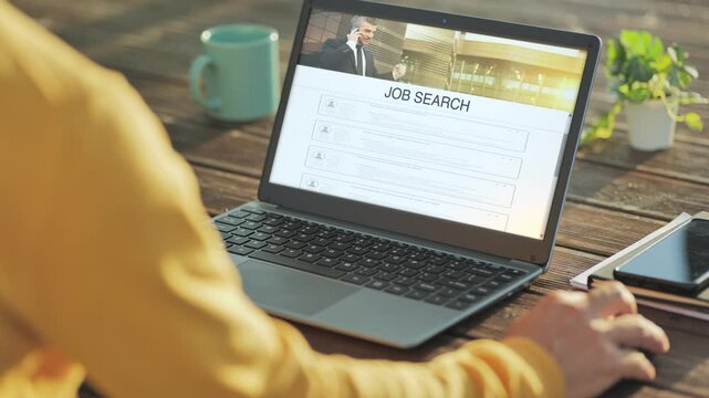 Back view of male using computer on the wooden table outdoor searching job online on internet,person search vacant job using laptop app