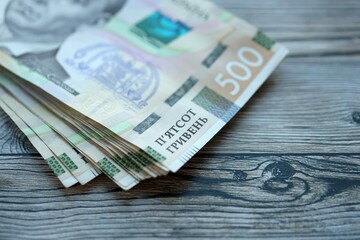 Many five hundred hryvnia money bills lies on wooden background. Ukrainian national currency close up