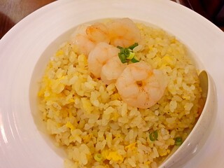 Chinese shrimp fried rice. Flatlay shrimp fried rice served on a white plate on a marble top table. It is served in most Chinese restaurant in asian countries