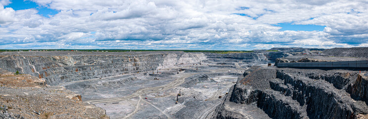 Panoramic view of the vast Malartic gold mine in Quebec, Canada, showcasing its impressive scale under a dynamic sky. Perfect for industrial and geological themes.