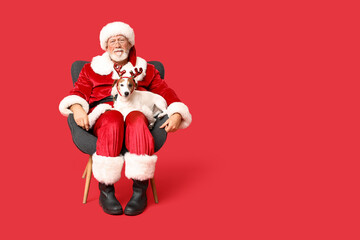 Santa Claus with cute Jack Russell Terrier dog in reindeer horns on red background