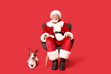 Santa Claus with cute Jack Russell Terrier dog in reindeer horns on red background