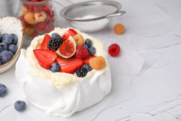 Pavlova cake (meringue dessert) with whipped cream, fresh berries and fig on white table, closeup. Space for text