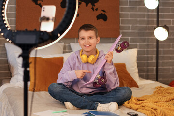Teenage boy blogger with skateboard recording video in bedroom © Pixel-Shot