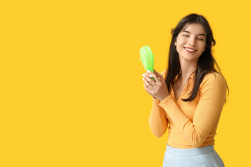 Young woman with mini fan on yellow background