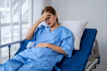 Fototapeta premium A woman in a blue hospital gown is laying on a hospital bed