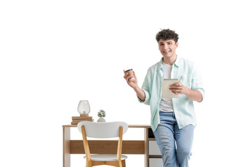 Young man with coffee cup and notebook near desk on white background