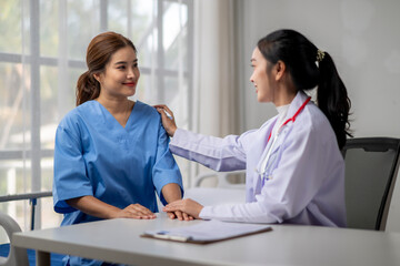 A woman in a blue scrubs is comforting a woman in a white scrubs