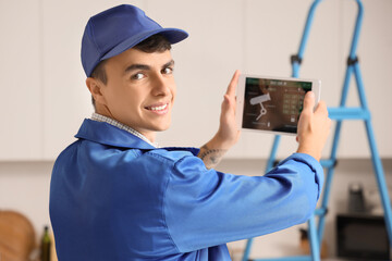 Male worker with tablet installing alarm system in house