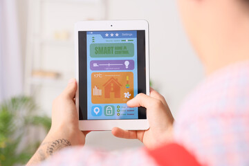 Male worker holding tablet with installed alarm system in house, closeup