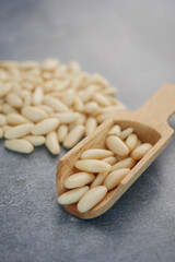 Wooden Spoon Filled with Fresh Raw Pine Nuts on Grey Background