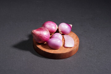 Red onion on wooden bowl isolated on black background.