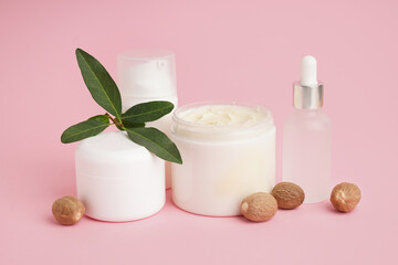 Jar with shea butter and cosmetics products on pink background