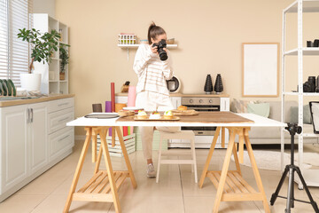 Young female photographer taking food pictures in kitchen