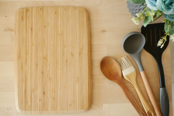 A crafted Wooden Cutting Board with Essential Cooking Utensils on the Kitchen Counter