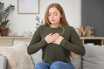 Young woman calming herself during panic attack on sofa at home