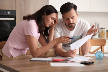 Young couple doing calculation in kitchen. Bankruptcy concept
