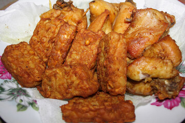 Photo of fried chicken and tempeh on a white plate, traditional Indonesian food