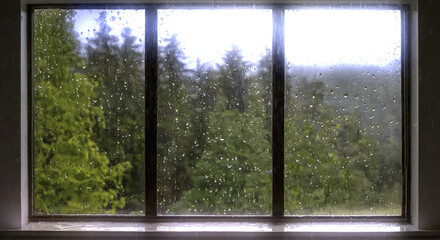Fototapeta premium 雨の降る山・山林・森林の風景 ガラス窓についた雨粒 滴のついたガラス窓に透ける緑の風景 霧の立ち込める山肌 アウトドア・キャンプの背景イメージ