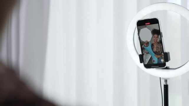 Rear view behide woman influencer shoot live stream vlog video review clothe crucial social media or blog. Girl with apparel studio lighting for marketing recording session broadcasting online