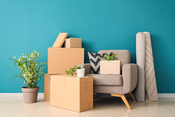 Armchair with cardboard boxes and plants near blue wall in room