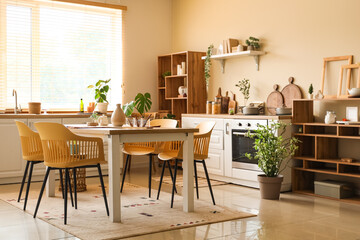 Wooden dining table, armchairs, shelving unit and counters in interior of kitchen