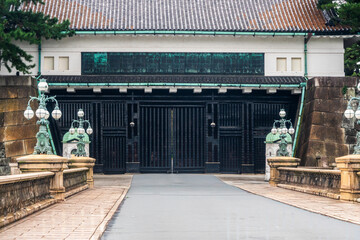 Entry gate to historical site surrounded by decorative lanterns and stone structures in Japan