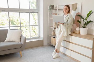Young woman with laptop video chatting near commode at home
