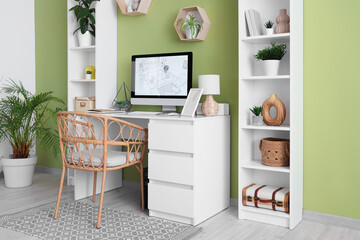 Interior of designer's office with workplace, shelf units and plants