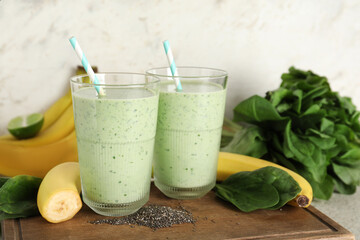 Glasses of fresh spinach smoothie with bananas and chia seeds on white background