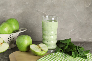 Glass of fresh spinach smoothie with apples on grey background