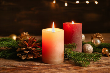 Burning candles and Christmas lights on table against dark background