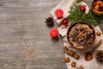 Bowl of traditional Ukrainian Kutya dish with coniferous branches and burning candles on wooden background