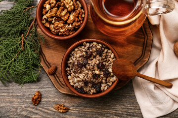 Bowls of traditional Ukrainian Kutya dish with coniferous branches and jug of uzvar on wooden background