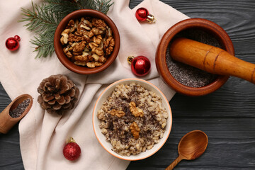 Bowls of traditional Ukrainian Kutya dish with fir branch and Christmas balls on black wooden background