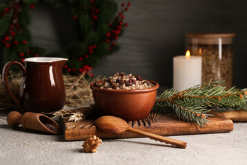 Bowl of traditional Ukrainian Kutya dish with fir branch and burning candle on white table