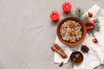 Bowl of traditional Ukrainian Kutya dish with Christmas tree branch and burning candles on grey background