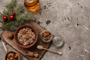 Bowl of traditional Ukrainian Kutya dish with fir branch and jug of uzvar on grey background