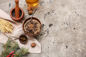 Bowl of traditional Ukrainian Kutya dish with honey and Christmas tree branch on grey background