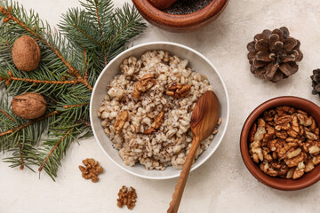 Bowl of traditional Ukrainian Kutya dish with Christmas tree branches and pine cones on white background