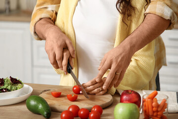 Married couple cutting tomato in kitchen, closeup