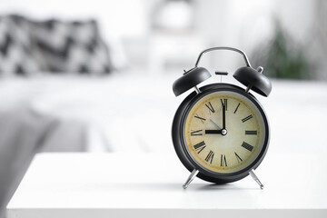 Retro alarm clock on table in bedroom, closeup
