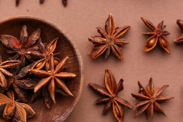 Wooden bowl with aromatic star anise on color background