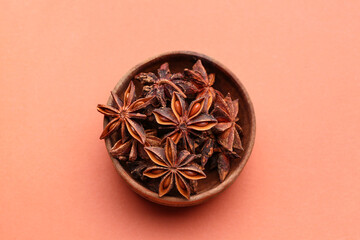 Wooden bowl with aromatic star anise on color background