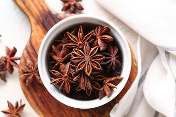 Wooden board with bowl of aromatic star anise on light table