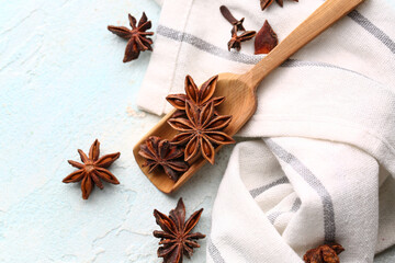 Wooden scoop with aromatic star anise and napkin on light background