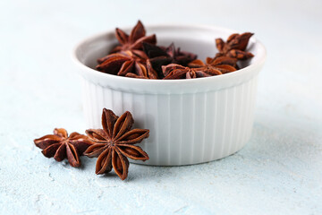 Bowl with aromatic star anise spice on light background