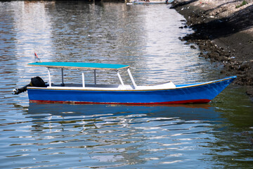 Blue wooden boat resting peacefully on the shores of Losari Beach, Makassar. Blue water and the clear sky