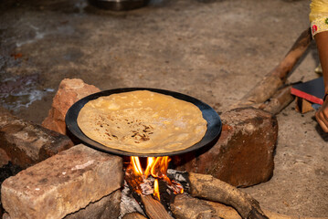 A village woman makes bread on the stove. cooking bread in clay stove , chula , makeing bread , roti , in village